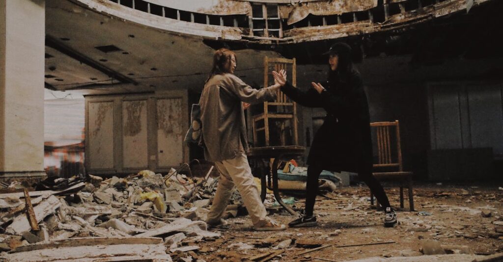 Two individuals pretend to fight in an abandoned, decaying building filled with rubble.